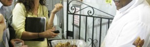 Man holds a platter of meat and a woman tastes meat on a toothpick and smiles