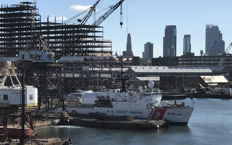 USCG Cutter in front of a construction project with several office buildings in Downtown Brooklyn and the Williamsburg Savings Bank Tour in the background