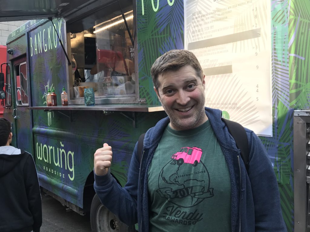 Brian wearing a green Vendys t-shirt standing in front of a food truck.