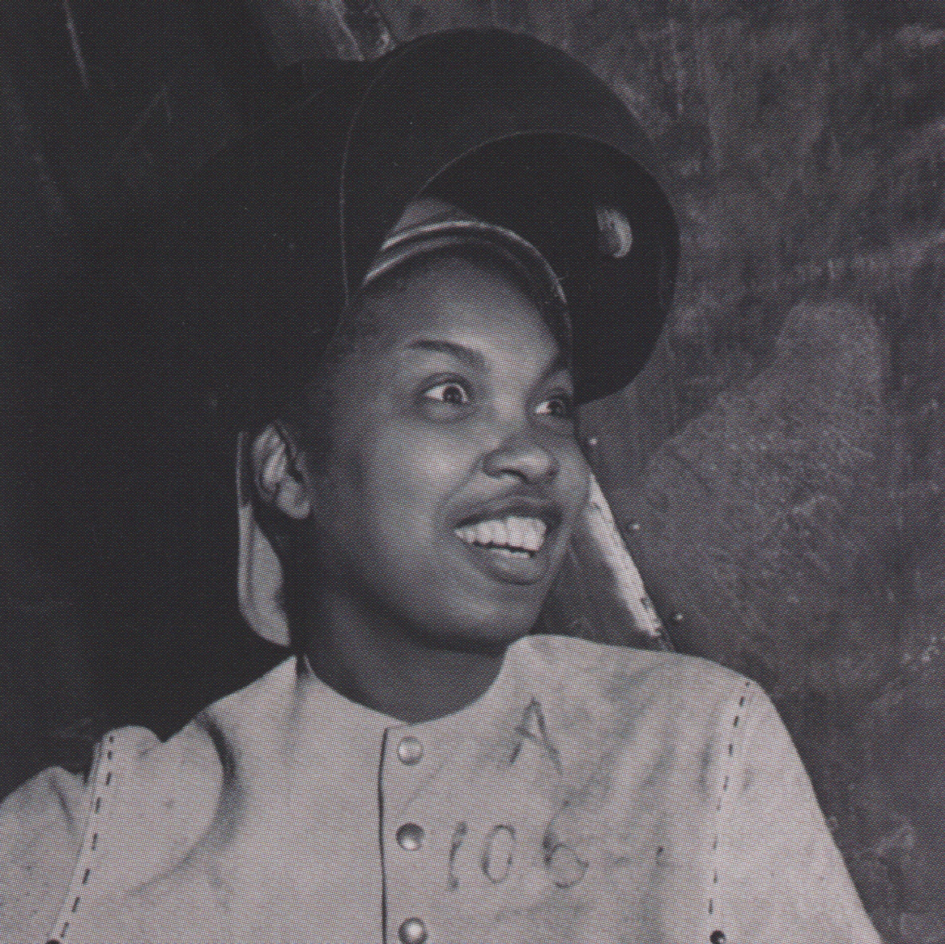 An African-American female wearing a welder's helmet flipped up. She is smiling and looks surprised.