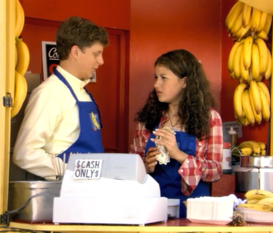 Still from Arrested Development, George Michael and Maeby working the banana stand at the cash register.