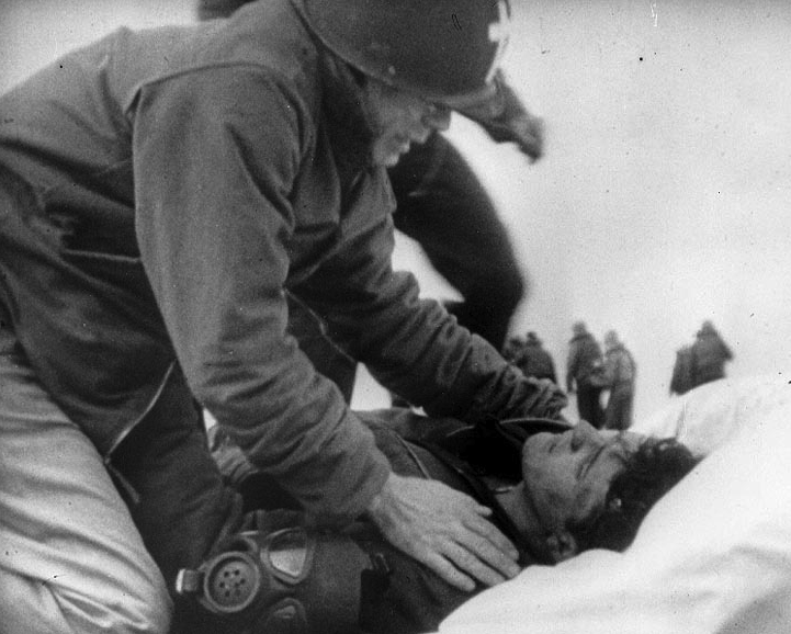 Chaplain Joseph O'Callahan assists wounded men during the attack of March 19, 1945.