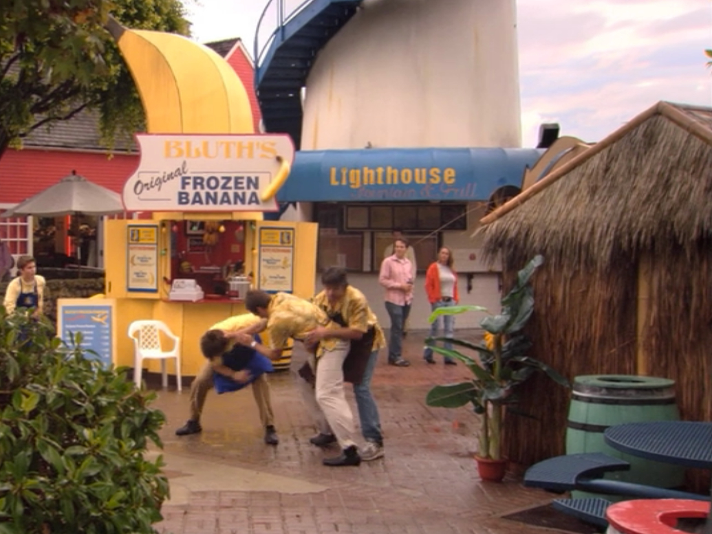 Still from Arrested Development, Michael, GOB, and Steve Holt flighting in front of the banana stand.
