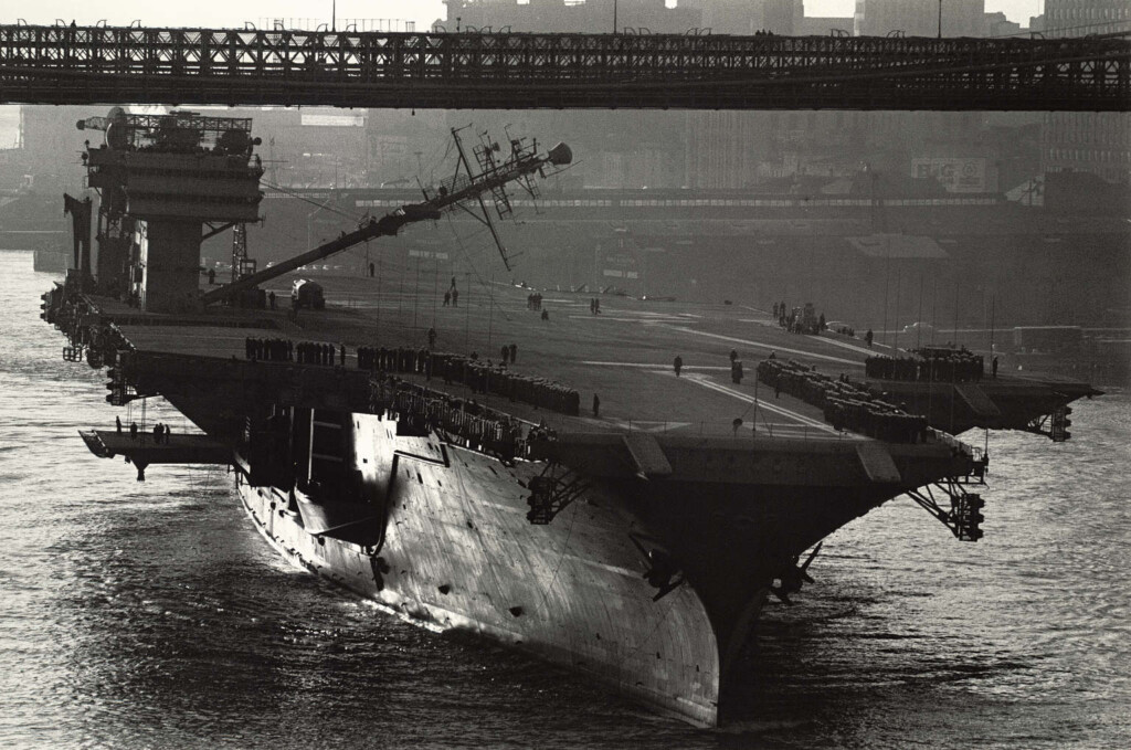 USS Constellation passes under the Brooklyn Bridge with folding mast, 1962.