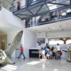 Photo of the lobby of BLGD 92 showing a large anchor and visitor services desk with a staff member and group of visitors gathered around it