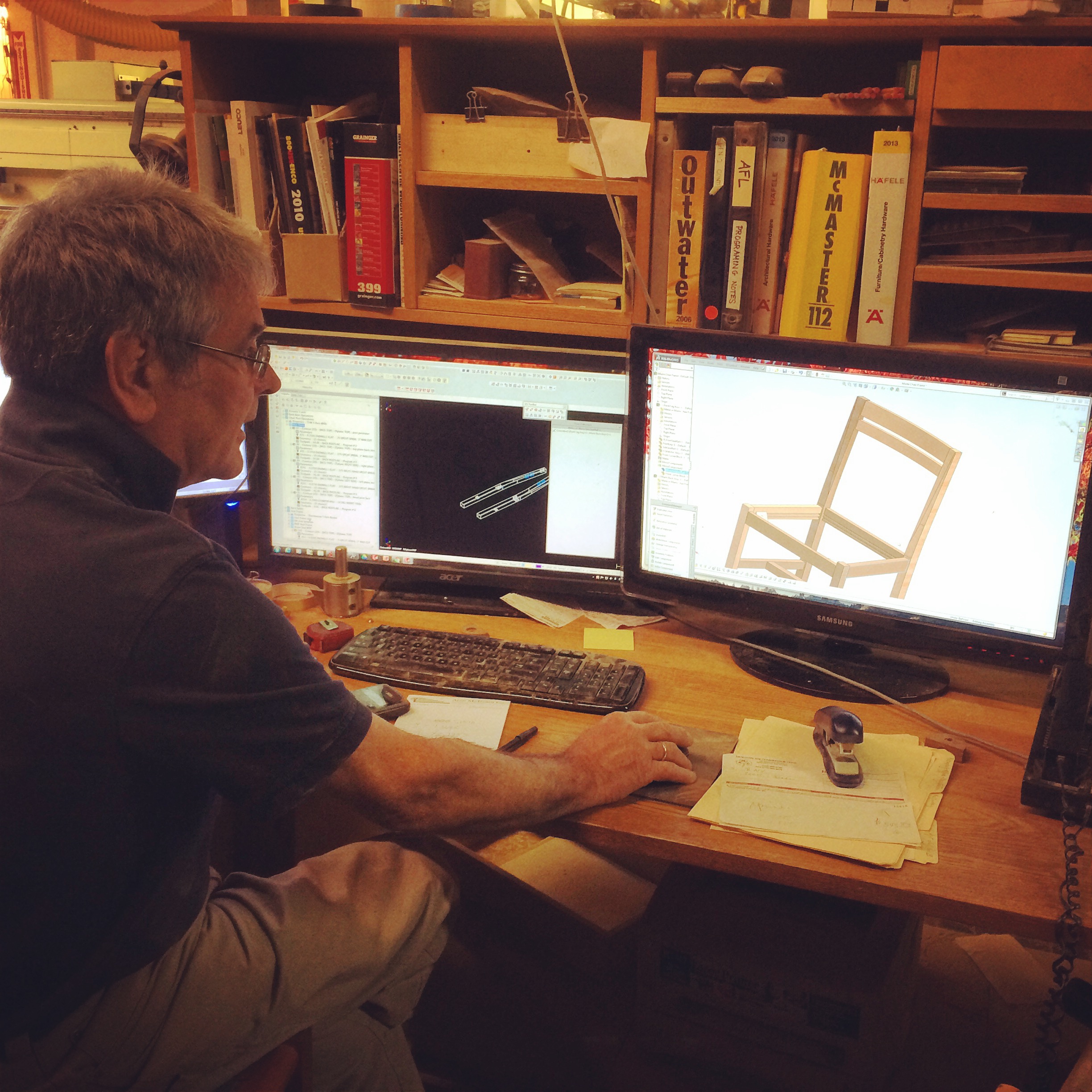 Sitting at his desk using a mouse and looking at a screen with a chair on it, Scott Jordan builds a chair, virtually.