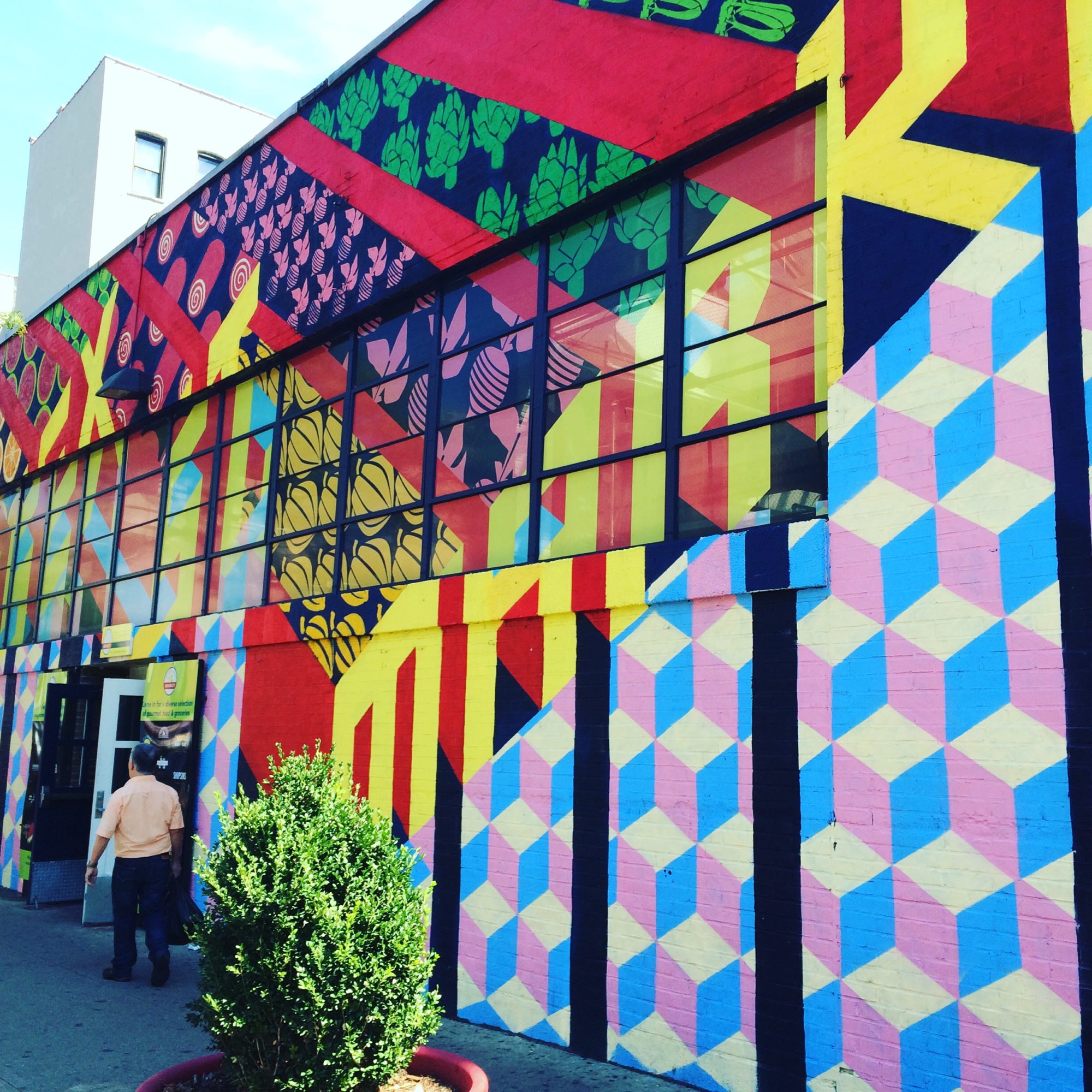 The outside of a market that's painted colorfully with designs that include painted vegetables, fruit, and geometric shapes