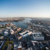 Aerial view that shows the Brooklyn Navy Yard with Wallabout Bay, the East River, and the Manhattan and Williamsburg Bridges and Manhattan in the background