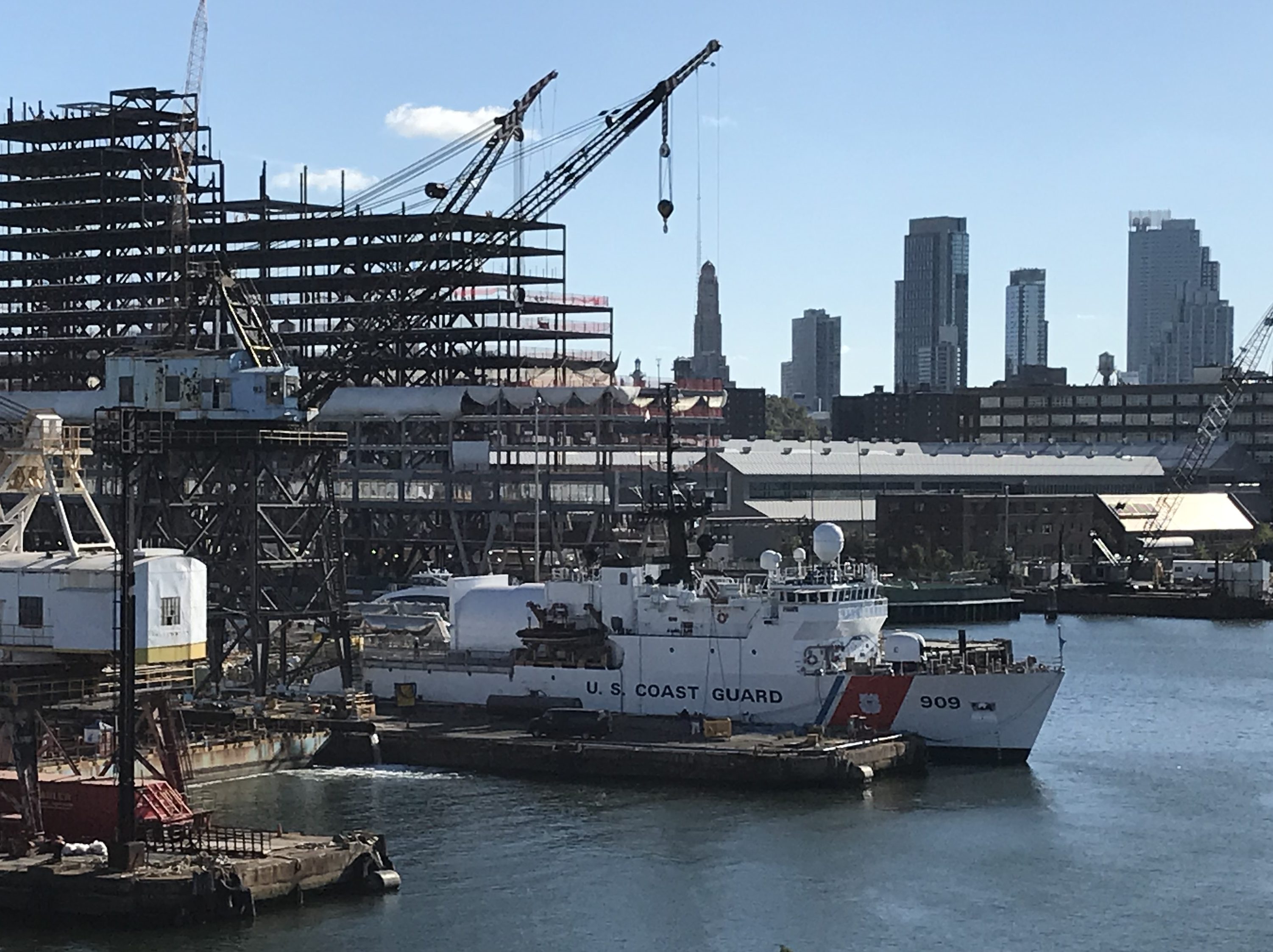 USCG Cutter in front of a construction project with several office buildings in Downtown Brooklyn and the Williamsburg Savings Bank Tour in the background