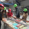 A tour at IceStone with 7 people looking at and handling samples of counter tops in a factory space