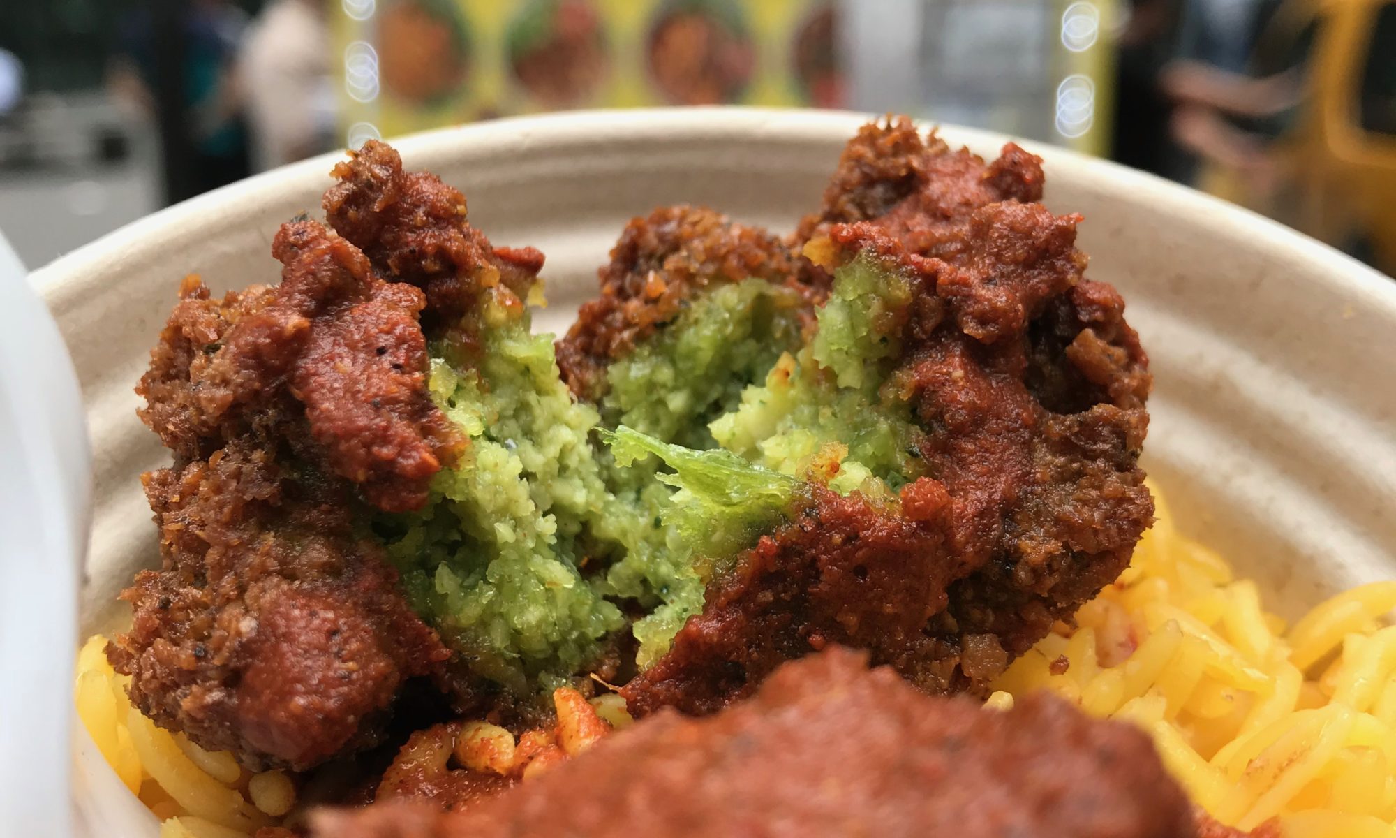 Falafel over yellow rice in a bowl from Adel's No. 1 Halal with bright yellow food cart in background