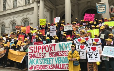 Street vendors rally on the steps of city hall with signs that read I love immigrant NY and Support NYC smallest businesses and Help us to serve you