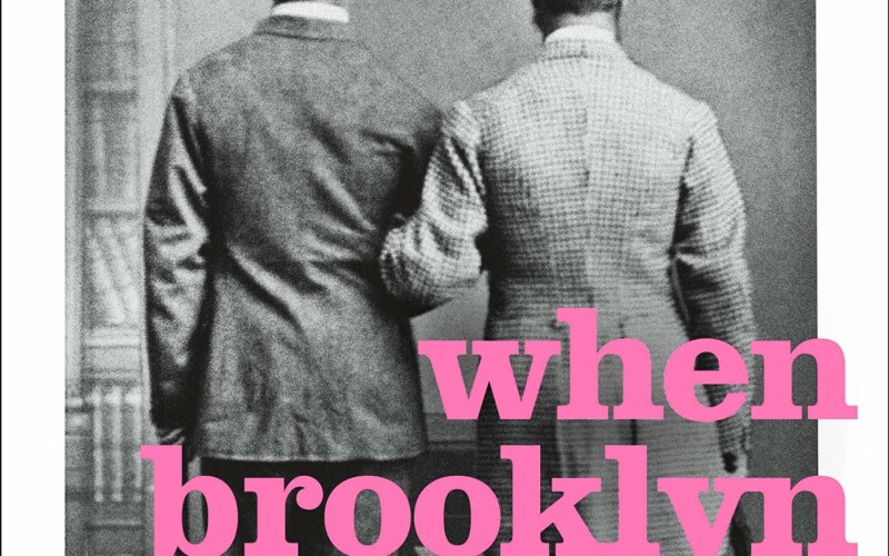 Black and white photo of two men turned away from the camera with linked arms with pink text overlay that reads, "When Brooklyn was Queer"