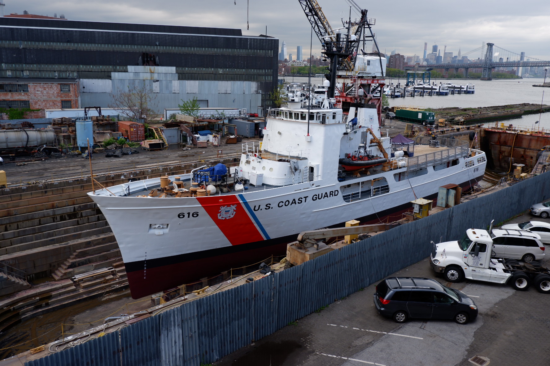 Coast Guard Cutter in a granite dry dock at the Brooklyn Navy Yard with the East River and Manhattan skyline in the background