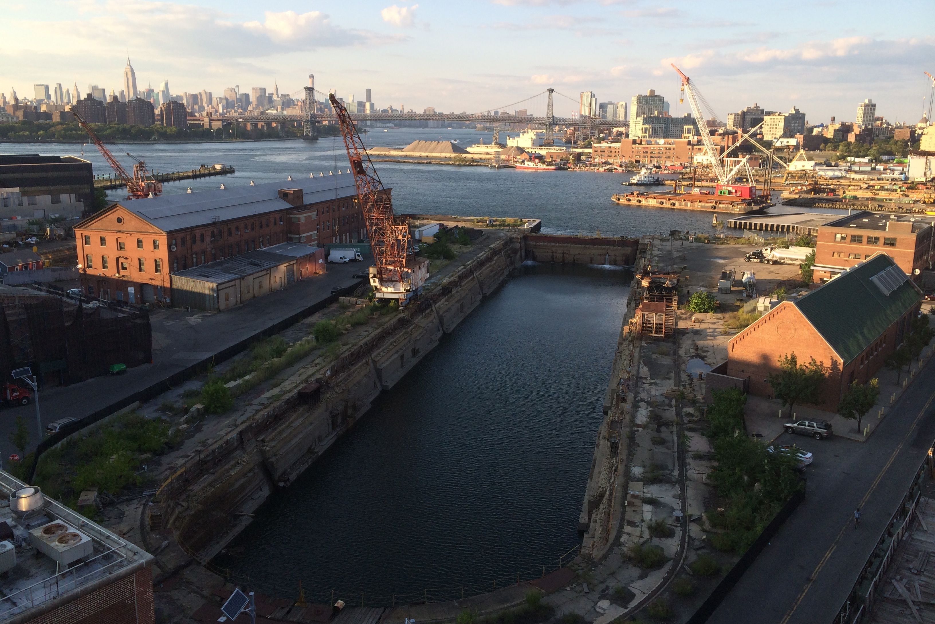 Photo at dusk from rooftop of Brooklyn Navy Yard showing the dry dock, bring buildings and cranes.