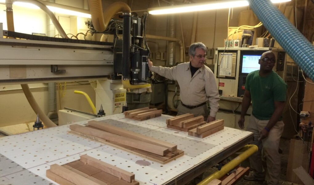 Scott Jordan standing in front of a CNC router with wooden parts