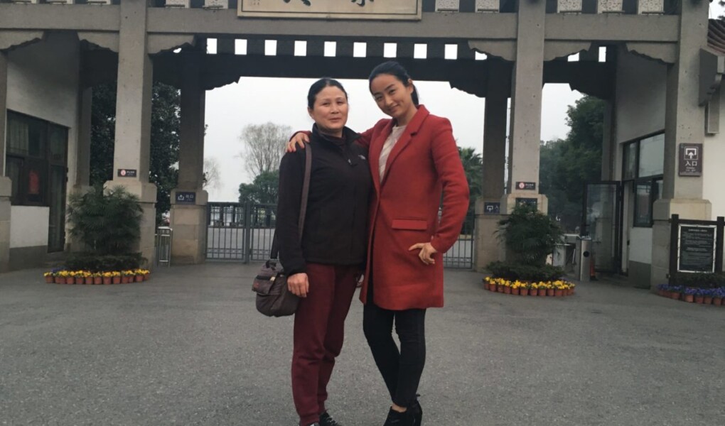 Two women standing front of a structure with Chinese characters
