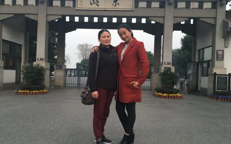 Two women standing front of a structure with Chinese characters